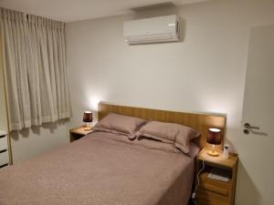 a bedroom with a bed and two night stands with lamps at Apartamento Frente pra Praia em Resort in Arraial do Cabo