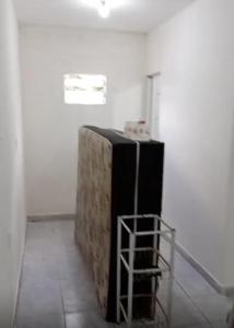 a black refrigerator in a white room with a shelf at Kitnet in Recife
