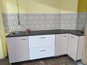 a kitchen with white cabinets and a sink at Hills Vacation Hostel in Darjeeling