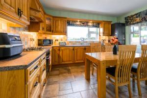 a kitchen with wooden cabinets and a wooden table with a wooden tableablish at Rosies Cottage in Rostrevor +138 photos