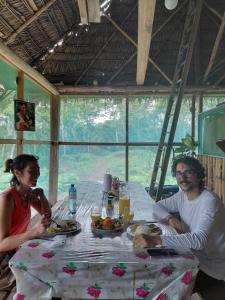 un hombre y una mujer sentados en una mesa con comida en Amazon tucuxi, en Islas Timicuro