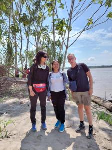un grupo de tres personas de pie junto al agua en Amazon tucuxi, en Islas Timicuro