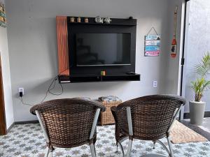 a living room with two wicker chairs and a television at Casa duplex compacta Top in Guarapari