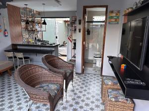 a living room with wicker chairs and a television at Casa duplex compacta Top in Guarapari