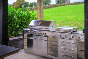 a grill on a patio with a lawn in the background at Rosies Cottage in Rostrevor