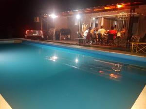 a swimming pool at night with people sitting at a restaurant at La Morada de sus Sueños Caeiro in Bialet Massé