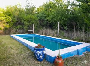 a blue swimming pool with two large vases next to it at La Morada de sus Sueños Caeiro in Bialet Massé