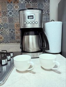 two cups on a counter next to a coffee maker at Dorotea Apartment in San Miguel de Allende