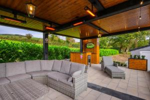 a patio with a couch and chairs under a wooden pergola at Rosies Cottage in Rostrevor