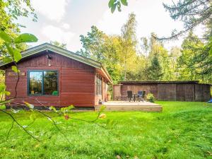 a small red cabin with a deck in a yard at 4 star holiday home in Ry in Ry
