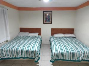 Dos camas una al lado de la otra en una habitación. en Hotel media luna, en San Luis Potosí