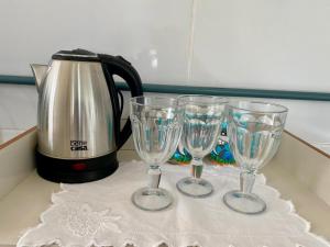 three wine glasses on a counter next to a tea kettle at Elegância Praia da Sereia in Vila Velha