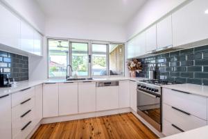 a kitchen with white cabinets and green tiles at The Fitzhill - East Dubbo Close to CBD in Dubbo +12 photos