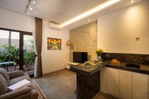 een keuken en een woonkamer met een bank en een televisie bij Harmoni Lane Studios in Seminyak