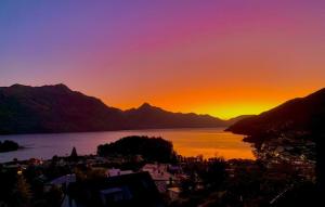 5 bedroom modern apartment in the heart of QT في كوينزتاون: غروب الشمس على جزء من الماء مع الجبال