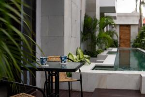een tafel en stoelen op een balkon met een zwembad bij Harmoni Lane Studios in Seminyak