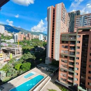a view of a city with a swimming pool and buildings at Apartamento Completo Poblado - Ubicacion Central con Parqueadero in Medellín