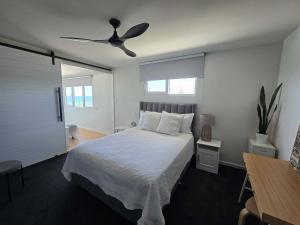 a bedroom with a bed with a ceiling fan at Flatrock Penthouse Ulladulla in Ulladulla +12 photos