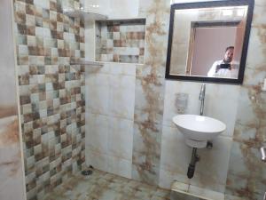 Ein Mann fotografiert ein Badezimmer mit Waschbecken. in der Unterkunft Good stay Nungambakkam in Chennai