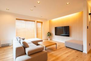 a living room with a couch and a tv at Natural Base 上富良野新築戸建て 駐車場3台 ファミリーオススメ マーケットすぐ in Kami-furano
