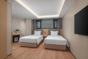 a hotel room with two beds and a flat screen tv at Holiday Inn Express Kunming Railway Station by IHG in Kunming