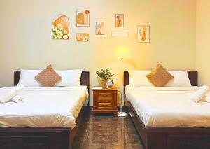 a bedroom with two beds and a night stand with a lamp at The Brownhaven Đà Lạt in Da Lat