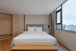 Un dormitorio con una gran cama blanca y una ventana. en Holiday Inn Express Kunming Railway Station by IHG, en Kunming