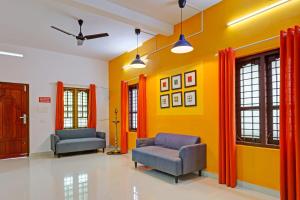 a living room with two chairs and a yellow wall at Capital O Pop Tavern Kazhakkottam in Trivandrum