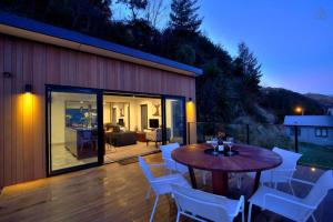 a patio with a wooden table and white chairs at Charming Lakeview Home with Remarkable Views in Frankton Wharf