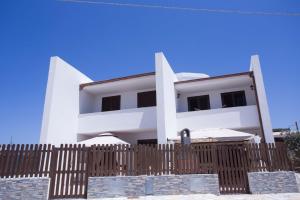 a white building with a wooden fence in front of it at Ascoltando Il Mare in Lido Signorino