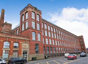a large brick building with cars parked in front of it at Preston City Apartment in Preston