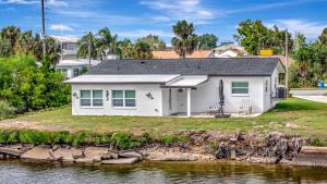 a white house on the shore of a body of water at Oyster House Waterfront 3b2b Kayaks BBQ Games in Hernando Beach