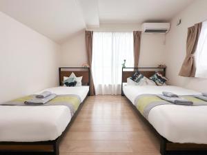 two twin beds in a room with a window at nestay villa tokyo itabashi in Tokyo