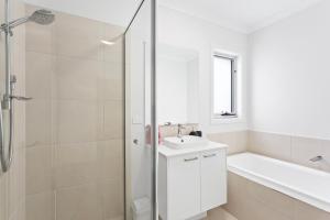 Un baño blanco con lavabo y ducha. en Modern Family Home sleeps 8, en Wimbledon Heights