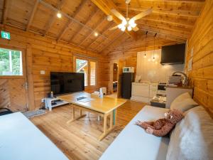a living room with a couch and a table at メロディーハウス 一棟貸新築ログハウス 広いデッキと庭 無垢材の香 小川のせせらぎ in Nasu