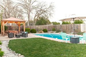 a backyard with a gazebo and a pool with chairs and an umbrella at Charade House in Redding