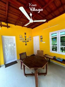 a dining room with a wooden table and yellow walls at Villaggio Homey in Munroe Island +59 photos
