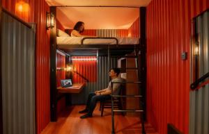 een man in een stoel in een kamer met stapelbedden bij hipstercity hostel in Singapore