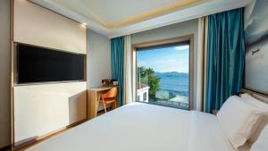 Un dormitorio con una cama grande y una ventana grande. en Floral Hotel Qingdao Dreamship Seaview Hotel, en Qingdao