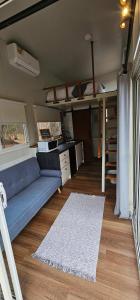 a living room with a blue couch and a desk at Hidden Camp's Loft House by Tiny Away in Kanighan