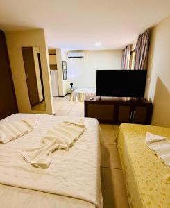 a hotel room with two beds and a flat screen tv at Belo apartamento no Solar Pipa in Pipa