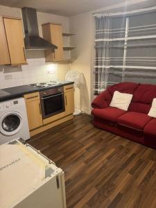 a living room with a red couch and a kitchen at Shirley Guest Flat 1 in Southampton