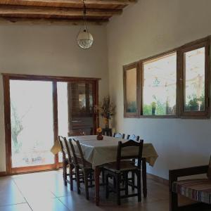 une salle à manger avec une table, des chaises et des fenêtres dans l'établissement Cabañas Bendita Tierra, à Los Molles