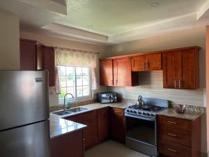 a kitchen with wooden cabinets and a stainless steel refrigerator at Portmore Country Club Cozy Retreat 1Bedroom in Portmore