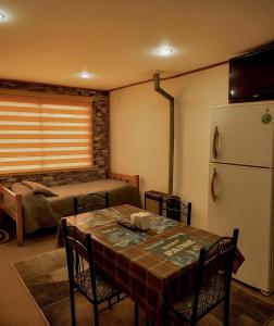 a room with a table and a bed and a refrigerator at Cabañas Puerto Natales centro in Puerto Natales