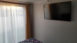 a flat screen tv hanging on a wall next to a window at Casa en Graneros in Graneros