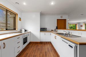 a kitchen with white cabinets and a wooden floor at Hideaway on Edgecumbe in Tauranga