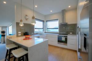 a kitchen with white cabinets and a large island with stools at Birch Haven Spa and Views in Queenstown