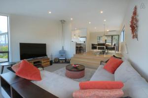 a living room with a couch and a television at Birch Haven Spa and Views in Queenstown