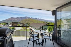 een balkon met een tafel en stoelen en bergen bij Remarkable Lake View in Queenstown